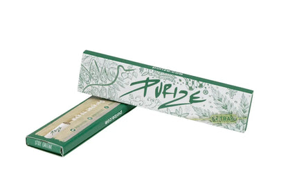 Eine grün-weiße Smokefy-Box mit PURIZE ® Papers`n`Tips mit Blumen- und Blattdesign ist teilweise geöffnet, um das ungebleichte Papier im Inneren zu zeigen. Die Verpackung wirbt mit „purize.com“ und dem Slogan „stay green“. Genießen Sie das Rollen mit natürlichem Gummi für geschmeidige Ergebnisse.