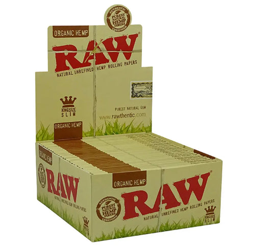 Eine Displaybox mit RAW Organic Hemp King Size Slim 50 Hefte je 32 Blatt Zigarettenpapier zeigt mehrere Packungen im Inneren. Die Verpackung ist beige mit roten und grünen Akzenten. Das auffällige RAW-Logo steht für die Qualität dieser Zigarettenpapiere.